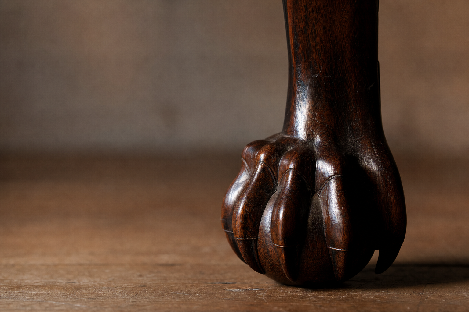 Macro detail of an 18th-century Chippendale ball-and-claw foot carved from dark mahogany with French-polish luster