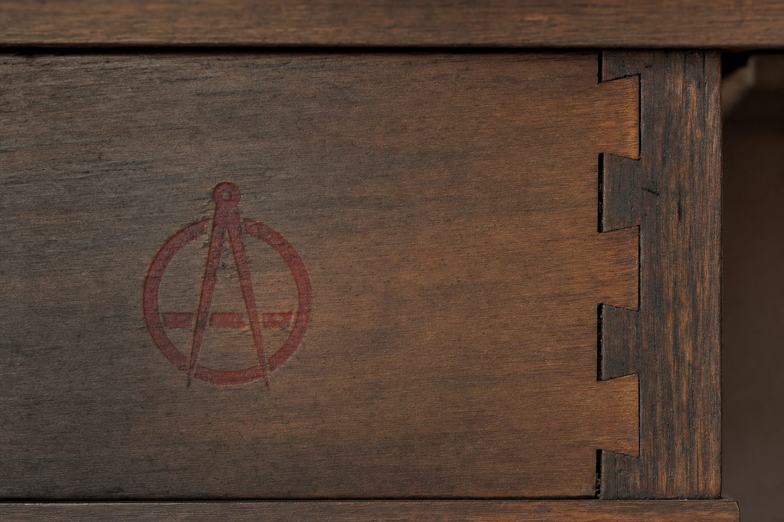 Macro detail of a Stickley compass-and-joiner shopmark branded into fumed quarter-sawn oak